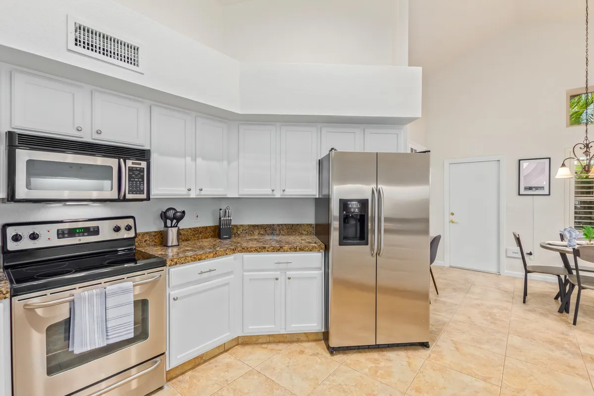A modern kitchen with stainless steel appliances, granite countertops, and crisp white cabinetry. The space feels bright, functional, and welcoming, ready for everything from gourmet feasts to casual BBQ prep.