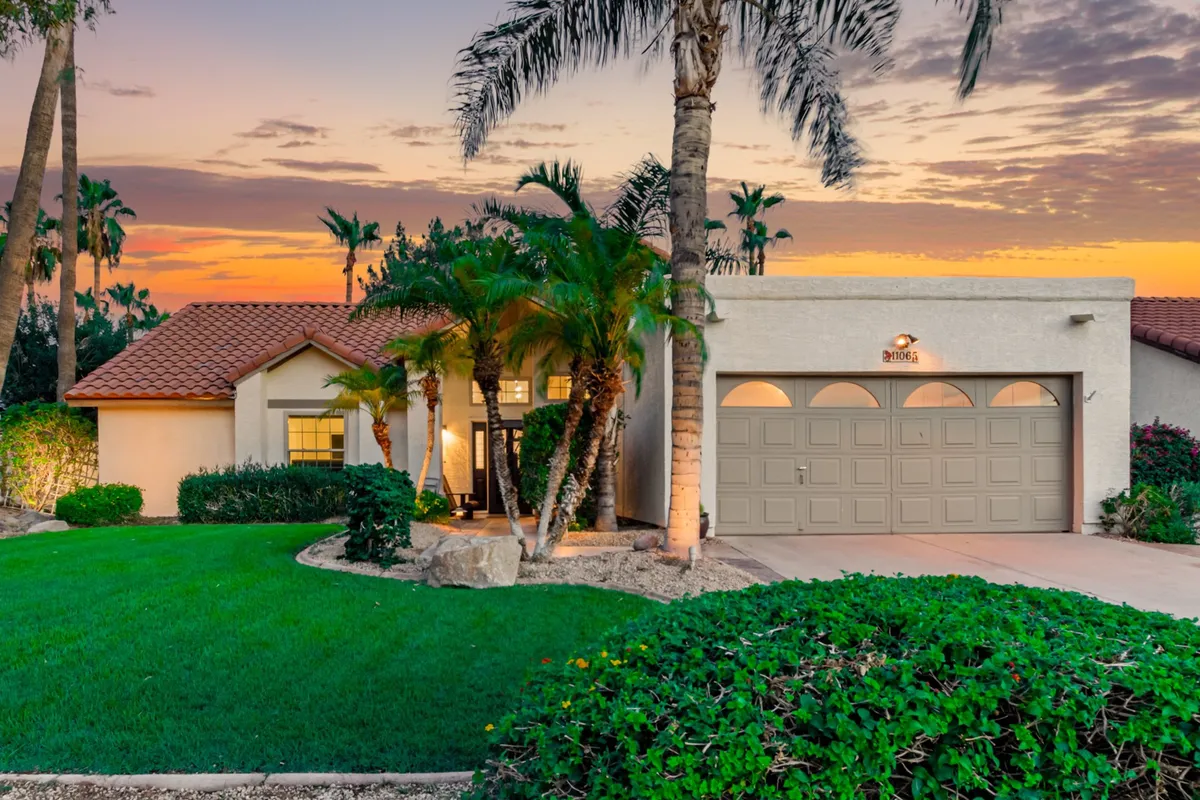 An inviting exterior view of the home, featuring a well-maintained lawn, palm trees, and a visible front door and garage. The fenced, open space conveys the sense of a secure, private backyard—ideal for pet owners seeking peace of mind.