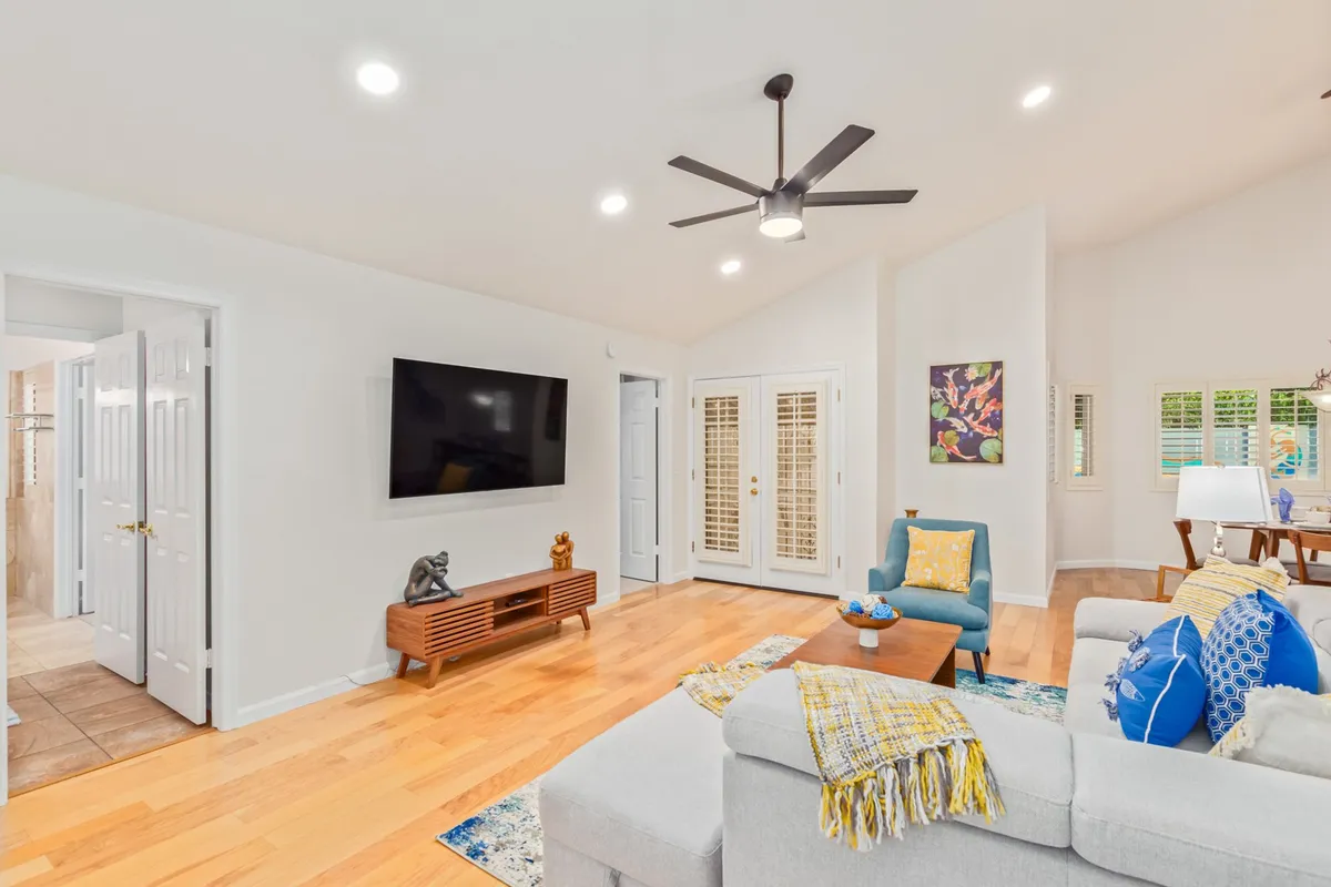 A cozy living area with a comfortable sofa adorned with decorative pillows, a wooden media console, ceiling fan, and tasteful wall art. The inviting ambiance highlights the comfort and thoughtful details throughout the home.