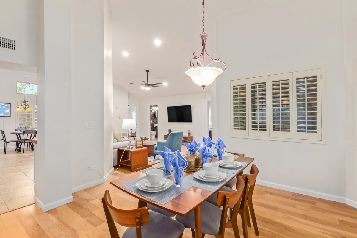 A beautifully set dining table with blue napkins under a statement light fixture. The living area is visible in the background, reinforcing the open-plan design and the inviting atmosphere for meals and social gatherings.
